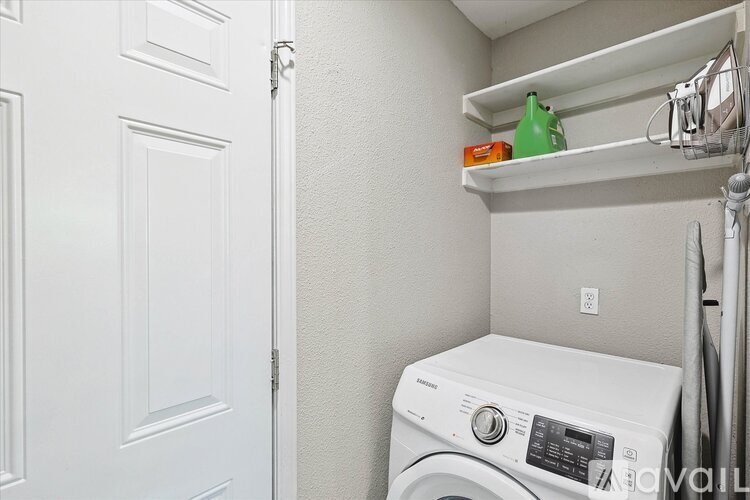 A white washing machine sits in a small laundry room.