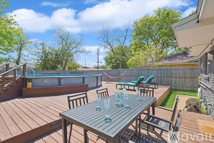 A wooden table is surrounded by chairs on a deck.