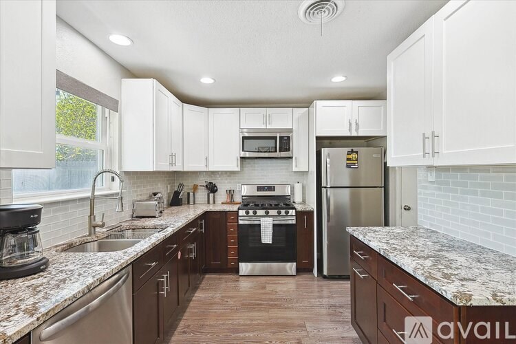 A kitchen with white cabinets and a marble countertop.