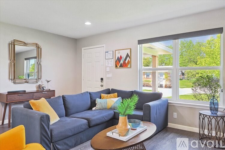 A living room with a blue couch, a mirror, a coffee table, and a potted plant.