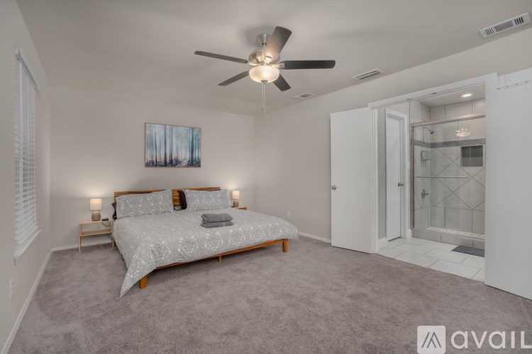 A bedroom with a bed, a ceiling fan, and a painting on the wall.
