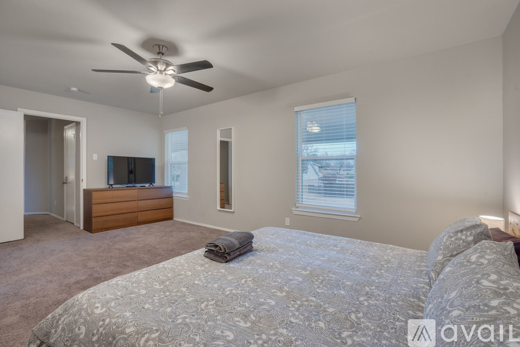 A bedroom with a large bed and a ceiling fan.