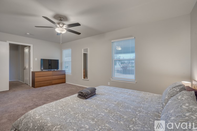 A bedroom with a large bed and a ceiling fan.