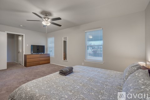 A bedroom with a large bed and a ceiling fan.