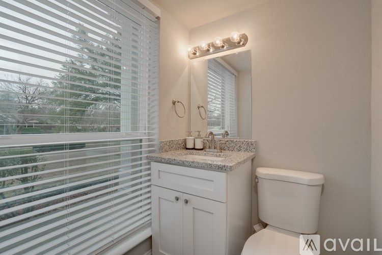 A bathroom with a toilet, sink, and window with blinds.