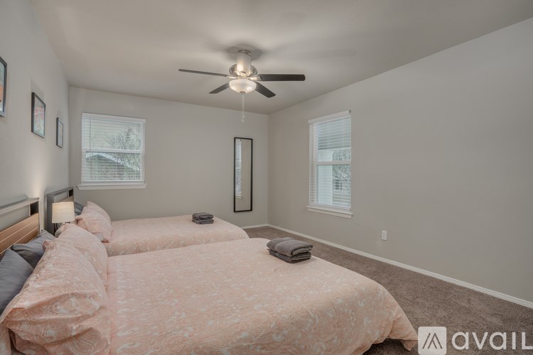 A bedroom with a bed, a ceiling fan, and two windows.