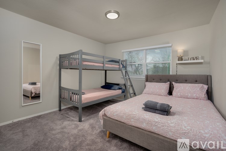 A bedroom with a bunk bed and a large bed with a pink bedspread.