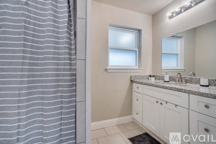 A bathroom with a shower curtain, a sink, and a mirror.