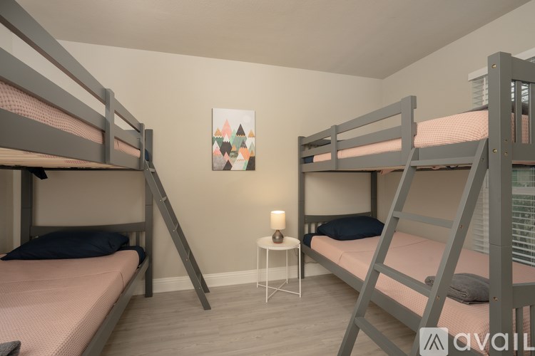 A room with two bunk beds and a small table with a lamp on it.