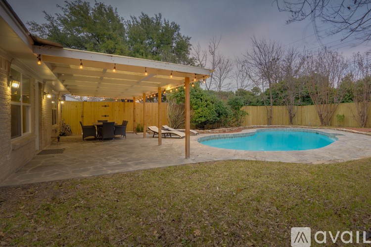 A backyard with a pool and a covered patio area.