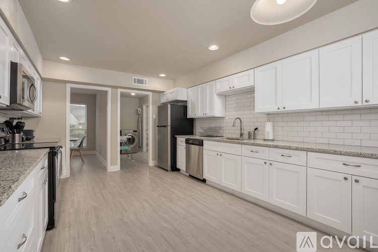 A kitchen with white cabinets and a black refrigerator.