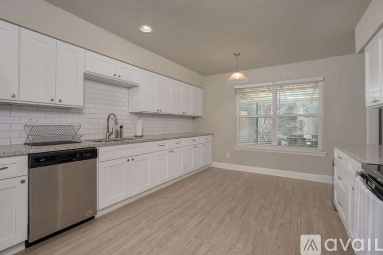 A kitchen with white cabinets and a wooden floor.