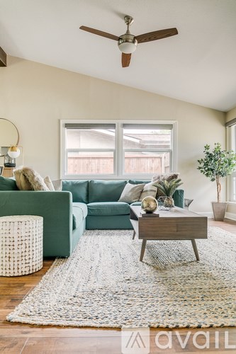 A living room with a green couch, a wooden coffee table, and a white rug.