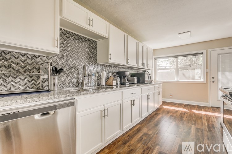 A kitchen with white cabinets and a silver dishwasher.