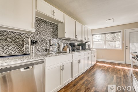 A kitchen with white cabinets and a silver dishwasher.