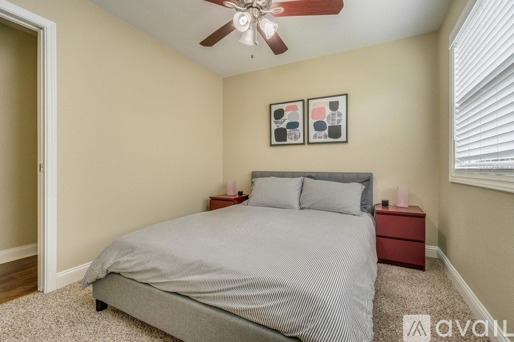 A bedroom with a bed, nightstands, and a ceiling fan.