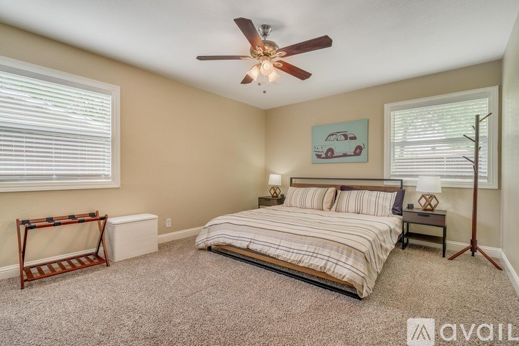 A bedroom with a bed, a fan, and a window with blinds.