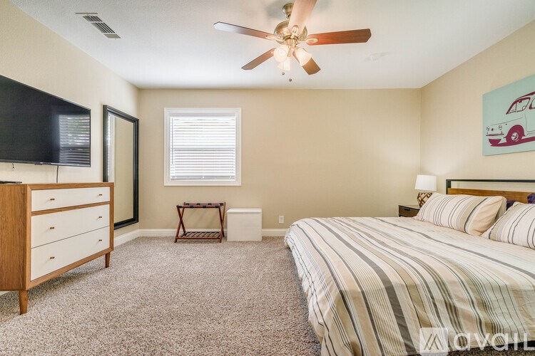 A bedroom with a bed, dresser, and television.