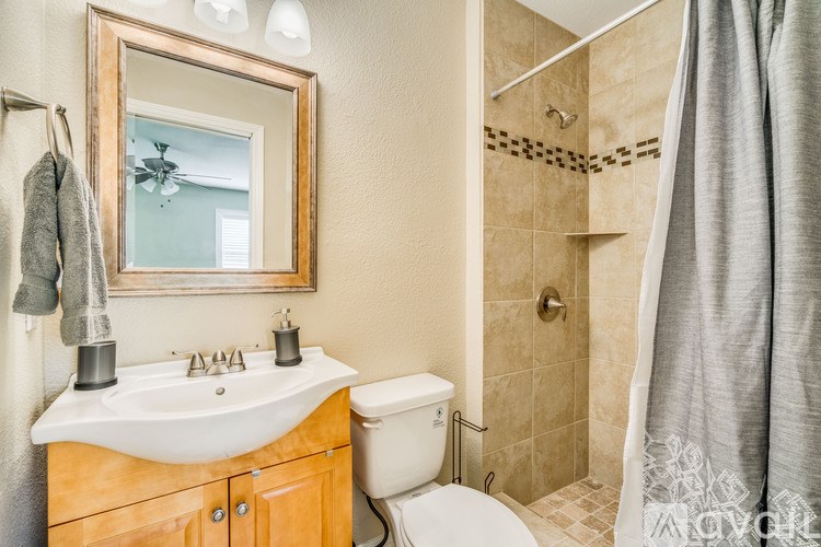 A bathroom with a white sink, toilet, and a mirror above the sink.