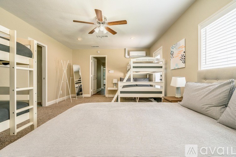 A bedroom with a bed, bunk beds, and a ceiling fan.