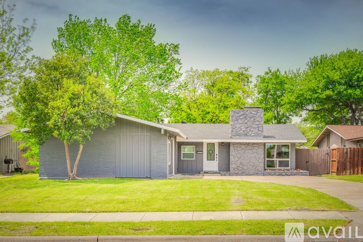 A house with a grey roof and a tree in front of it.