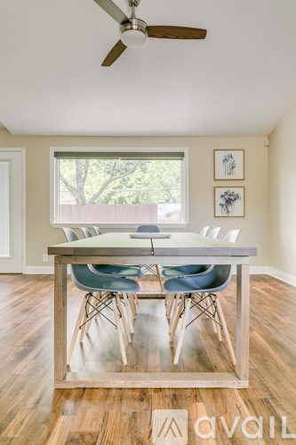 A room with a table and chairs and a fan.
