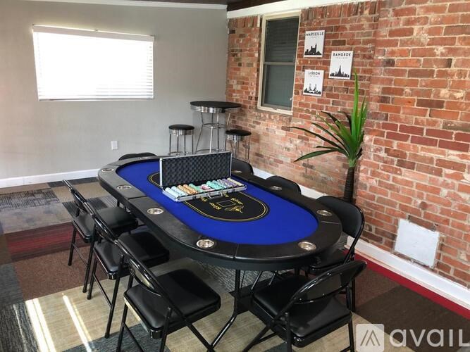 A poker table with chairs and a plant in a room with a brick wall.