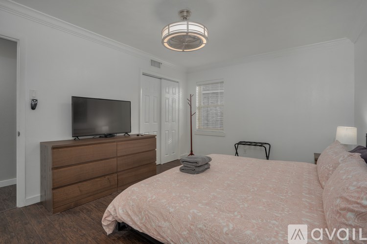 A bedroom with a bed, dresser, and television.