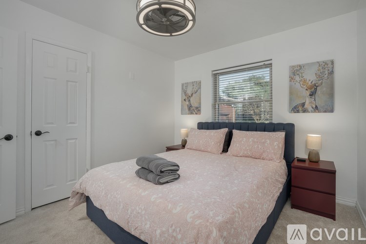 A bedroom with a bed, nightstand, and two framed pictures on the wall.