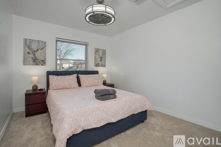 A bedroom with a bed, nightstands, and pictures on the wall.