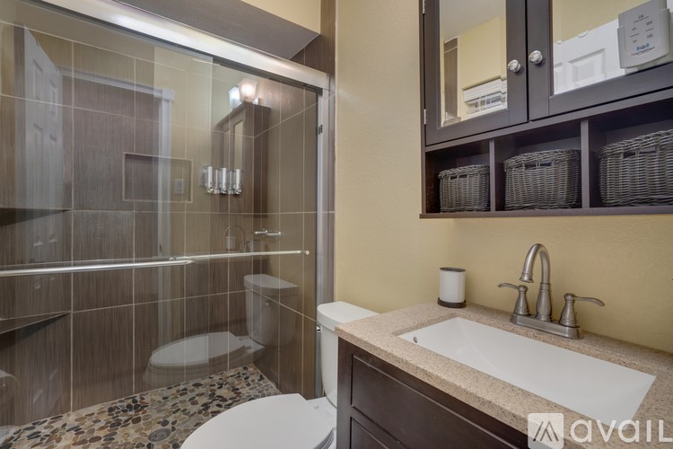 A bathroom with a glass shower stall and a sink with a counter.