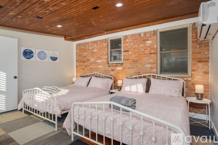 Two twin beds in a room with a brick wall.