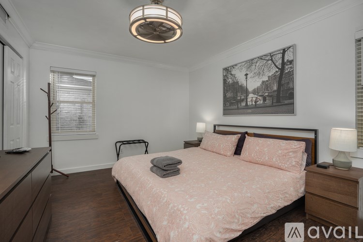 A bedroom with a bed, nightstand, and a painting on the wall.