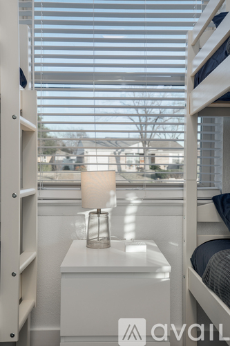 A white bedroom with a bunk bed and a window with blinds.