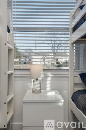 A white bedroom with a bunk bed and a window with blinds.