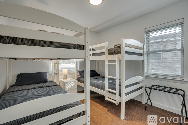 A room with white walls and wooden floors has two bunk beds.