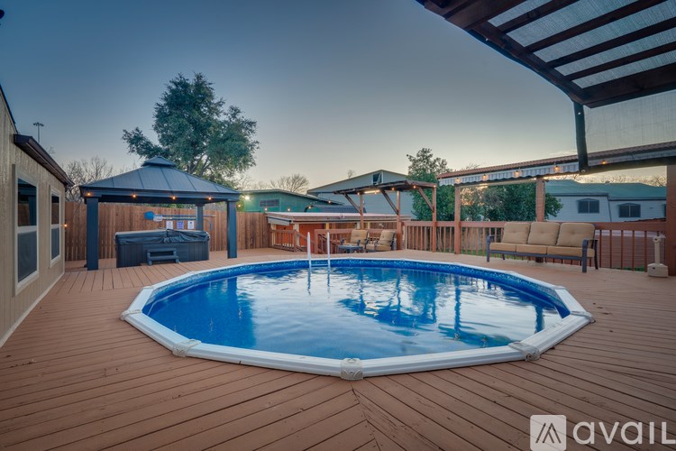 A wooden deck with a round blue pool in the middle.