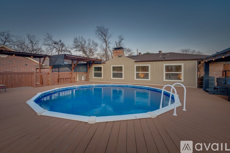 A pool in a backyard with a deck and two houses.