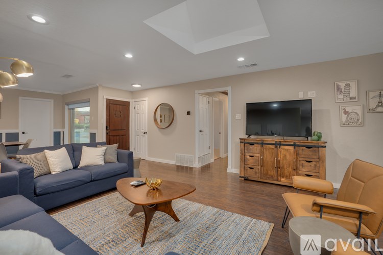 A living room with a blue couch, a wooden coffee table, and a flat screen TV mounted on the wall.