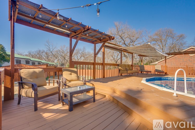 A wooden deck with a table and chairs overlooking a pool.