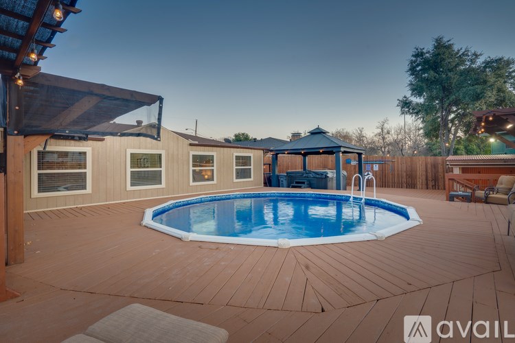 A wooden deck with a round blue pool and a gazebo.