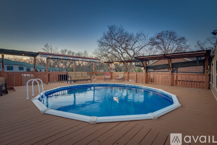 A pool with a deck and a building in the background.