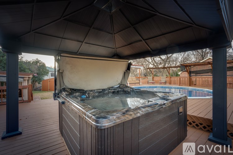 A hot tub is covered by a black umbrella.