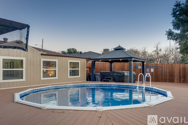 A pool with a deck and a gazebo in the backyard.