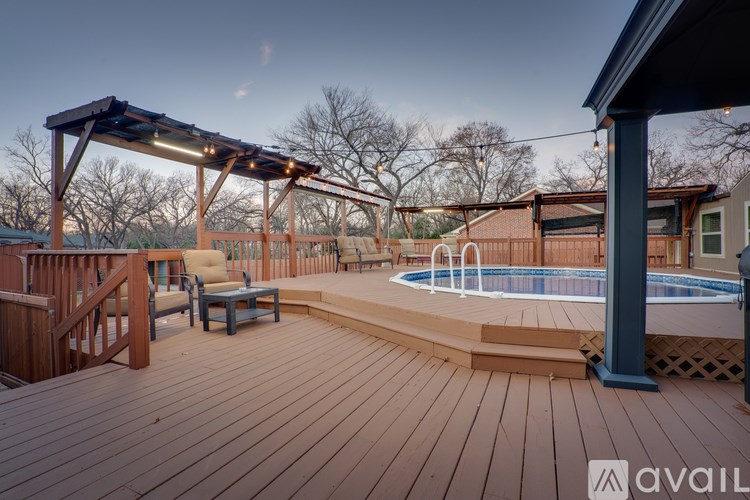 A wooden deck with a pool and a pergola.
