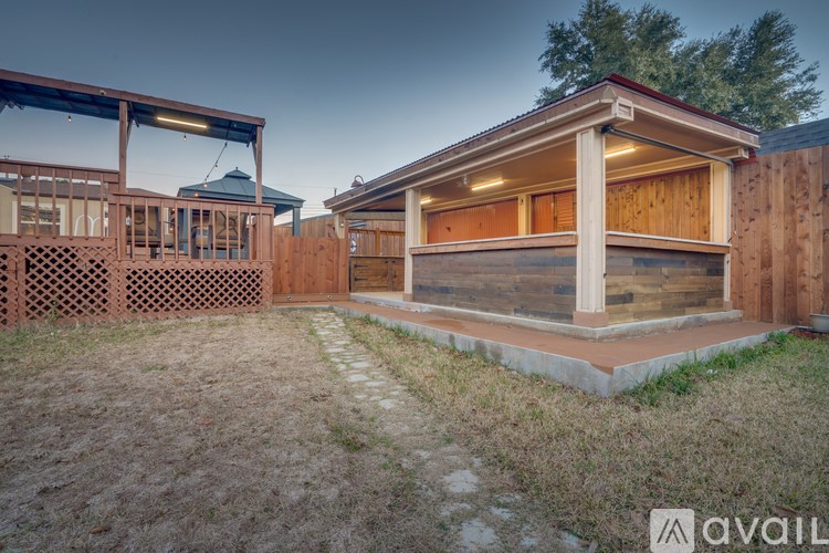 A wooden house with a porch and a gazebo-like structure in the backyard.