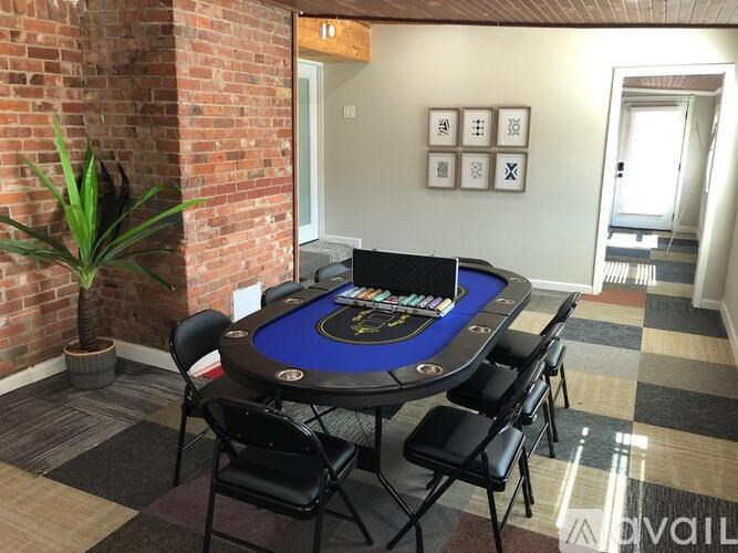 A poker table with chairs and a potted plant in a room with a brick wall.