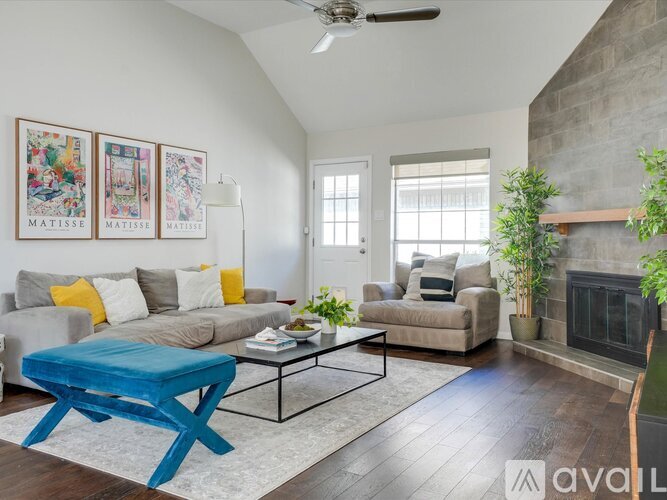 A living room with a blue ottoman and a fireplace.