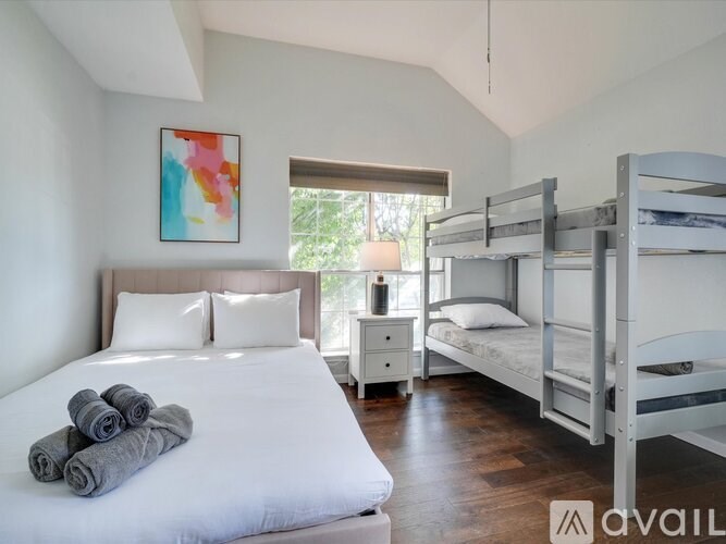 A bedroom with a white bed and a painting on the wall.