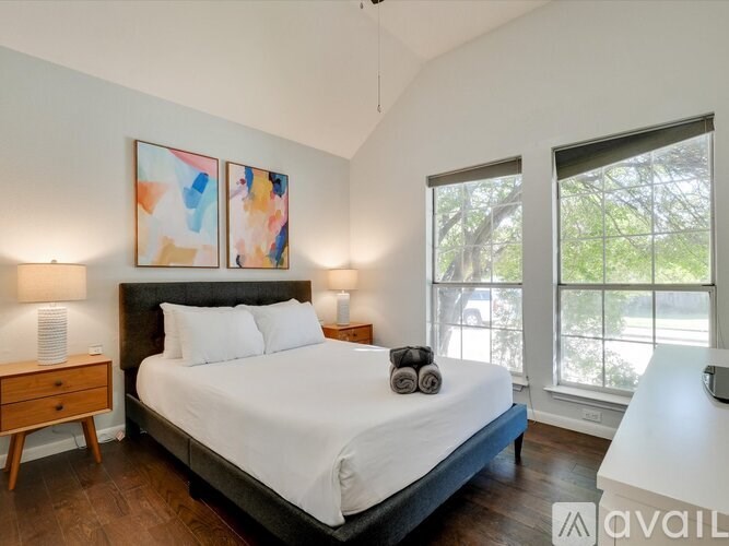 A bedroom with a large bed, two lamps, and a painting on the wall.